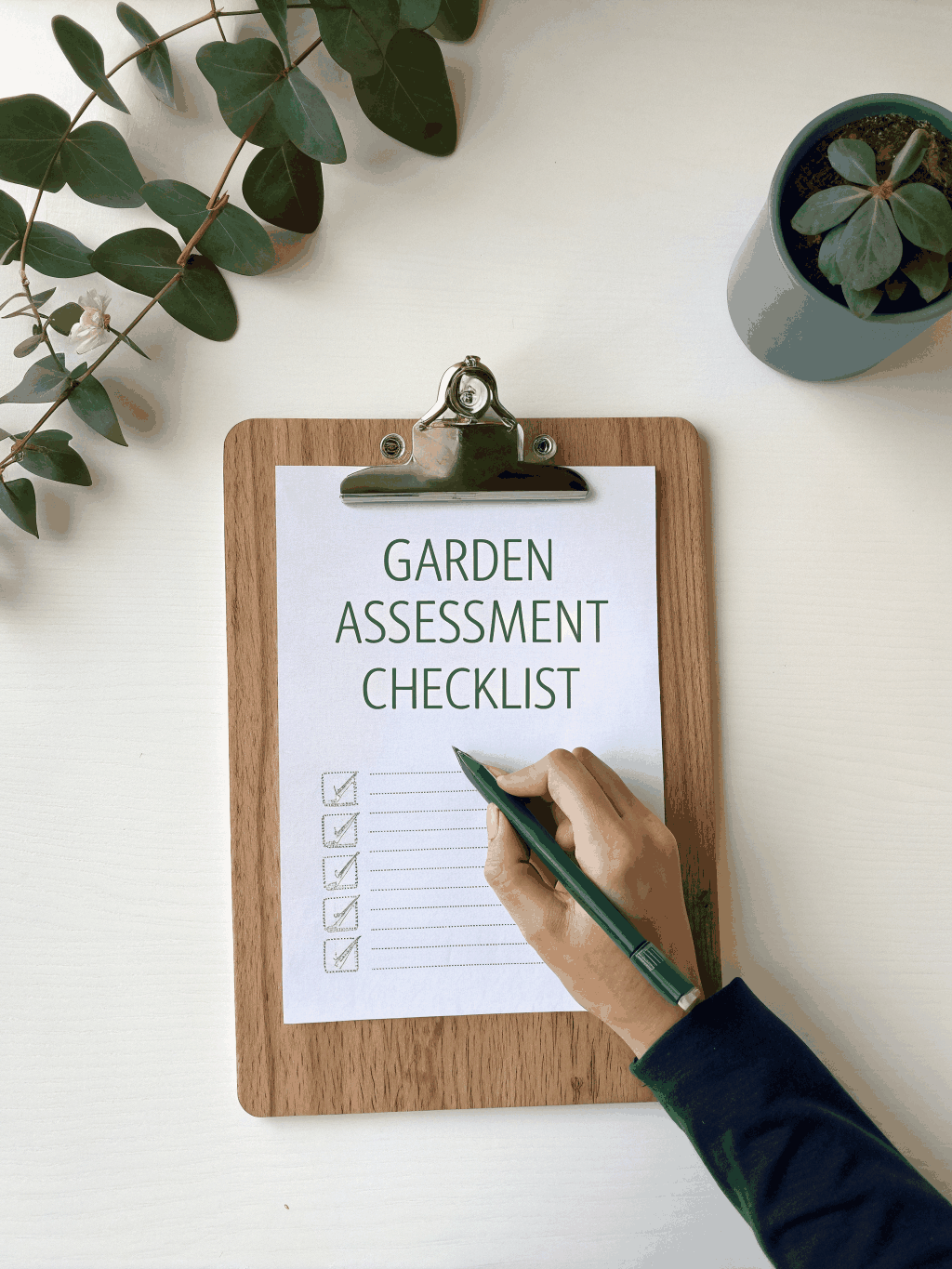 Clipboard with a blank checklist, pencil and small plant on a white desk